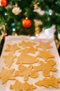 Close-up of uncooked gingerbread dough on white. tray, against the background of a decorated Christmas tree with balls Royalty Free Stock Photo