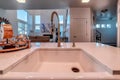 Close up of undermount sink with curved faucet on polished white countertop