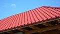 A close-up of an unfinished metal roof with red metal roofing tiles, wood ceiling joists, eaves, and roof beams Royalty Free Stock Photo