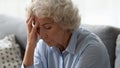 Close up unhappy older woman touching forehead, suffering from headache