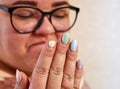 Close-up of unhappy young woman looking at a broken fingernail and sadness . multicolor nails manicure and broken nail Royalty Free Stock Photo