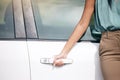 Close up of a unknown mixed race female standing and holding the handle of her new vehicle outside