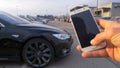 CLOSE UP: Unknown person holds a smartphone and steers car out of parking space.