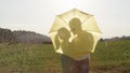 CLOSE UP: Young couple on romantic date is kissing hidden behind yellow umbrella