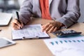 Close up of unrecognizable black woman in formal outfit filling up tables on clipboard next to electronic calculator Royalty Free Stock Photo