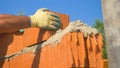 CLOSE UP: Unrecognizable builder lays a new brick on top of a wall in progress.