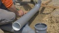 CLOSE UP: Unrecognizable builder marks a plastic sewage pipe with a pencil.