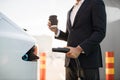 Close up of man holding coffee and charging electro car Royalty Free Stock Photo