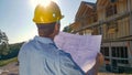 CLOSE UP: Unrecognizable construction site manager looks at the blueprints. Royalty Free Stock Photo