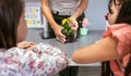 Female teacher hands showing pansy plant to her students in ecology classroom