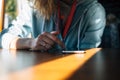 Close-up unrecognizable female touching mobile device screen with her finger. Young woman reading smart phone sitting at table in Royalty Free Stock Photo