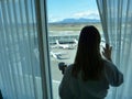 CLOSE UP: Unrecognizable girl holding the curtain while watching the airport.