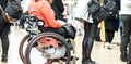 Close up of unrecognizable hanicapped woman on a wheelchair queuing in line to perform everyday tasks.