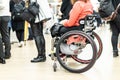 Close up of unrecognizable hanicapped woman on a wheelchair queuing in line to perform everyday tasks.