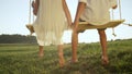 CLOSE UP Couple barefoot kids sitting on wooden swing holding hands Royalty Free Stock Photo