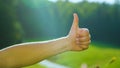 CLOSE UP Unrecognizable male hitchhiker lifts up his arm and gives the thumbs up