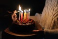 Close-up of unrecognizable man burning candles, woman holding in hands birthday cake with six burning candles in dark Royalty Free Stock Photo