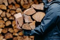 Close up of unrecognizable man dressed in jacket carries bundle of firewood, going to make fire outdoor. Winter is coming Royalty Free Stock Photo