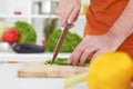 Close up of unrecognizable man`s hand chopping green onion with kitchen knife on cutting board. Royalty Free Stock Photo