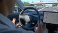 CLOSE UP Unrecognizable man tentatively lets go of the steering wheel of a Tesla