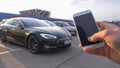 CLOSE UP: Unrecognizable person steers the high tech Tesla car with cell phone. Royalty Free Stock Photo