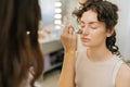 Close-up of unrecognizable professional female make-up artist applying cosmetic tonal foundation for face sculpting of Royalty Free Stock Photo