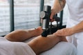 Close-up of unrecognizable professional male masseur massaging leg calf muscles using massage gun percussion tool of Royalty Free Stock Photo