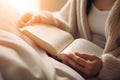 Close up unrecognizable smart girl woman reading book literature in cozy bed bedroom warm sunny lights relaxation