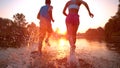 CLOSE UP Unrecognizable woman and man running towards sunset and splashing water Royalty Free Stock Photo