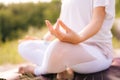 Close-up of unrecognizable woman sitting in lotus position and holding finger hand in Om position.