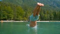 CLOSE UP: Unrecognizable young man having fun diving into the emerald lake. Royalty Free Stock Photo