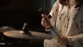 Close-up. An unrecognizable young girl energetically beats her drumsticks on an electronic hi-hat cymbal.