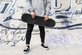 Close up of unrecognizable young man holding longboard or skateboard in the park. Royalty Free Stock Photo