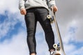 Close up of unrecognizable young man holding longboard or skateboard in the park. Royalty Free Stock Photo