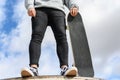 Close up of unrecognizable young man holding longboard or skateboard in the park. Royalty Free Stock Photo