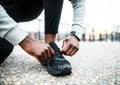 A close-up of a young sporty black man runner tying shoelaces outside in a city. Royalty Free Stock Photo