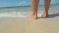 CLOSE UP: Unrecognizable young woman standing on sandy beach woman wets her feet Royalty Free Stock Photo