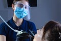 Close-up, from an unusual angle, view, a dentist using dental equipment treats a patient a girl with a tooth and oral cavity