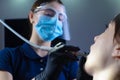 Close-up, from an unusual angle, view, a dentist using dental equipment treats a patient a girl with a tooth and oral cavity