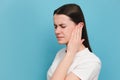 Close up of upset sad young millennial female holding painful ear, suddenly feeling strong ache, posing isolated on blue color Royalty Free Stock Photo