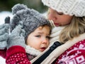 Close-up of upset small daughter in carrier and mother in winter nature. Royalty Free Stock Photo