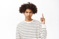 Close up of upset young boy pointing finger up, frowning and looking annoyed, showing smth upsetting, standing over Royalty Free Stock Photo