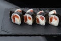 Close-up of uramaki sushi rolls with red caviar salmon tuna cucumber and avocado isolated on black background. Delicious Royalty Free Stock Photo