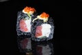 Close-up of uramaki sushi rolls with red caviar salmon tuna cucumber and avocado isolated on black background. Delicious Royalty Free Stock Photo