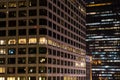 Close up urban scene of modern buildings at night with colorful glowing windows, lights and reflections