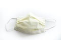 Close up of a used yellow doctors mask or nurse mask face covering looking straight down isolated on a white background