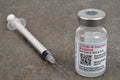 Moderna COVID-19 vaccine vial with syringe on gray background