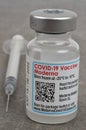 Moderna COVID-19 vaccine vial with syringe on gray background