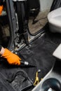 Close-up vacuum cleaning of dirty car floor with removed seats in detailing service. Worker of detailing service is Royalty Free Stock Photo