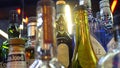 Close-up of variety of alcohol in bar. Frame. Colorful glass bottles stand on bar counter on background of bright lamps Royalty Free Stock Photo